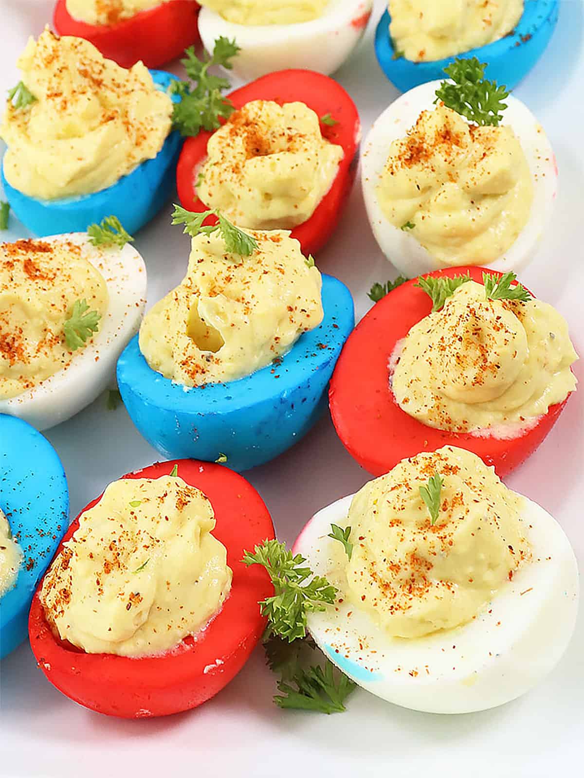 Closeup of red white and blue deviled eggs with filling.
