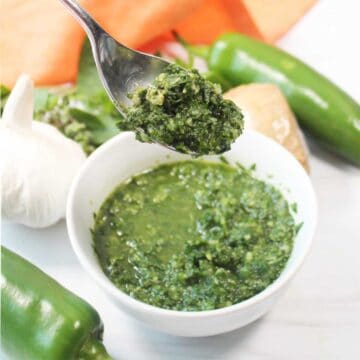 Lifting spoonful of sauce over bowl.