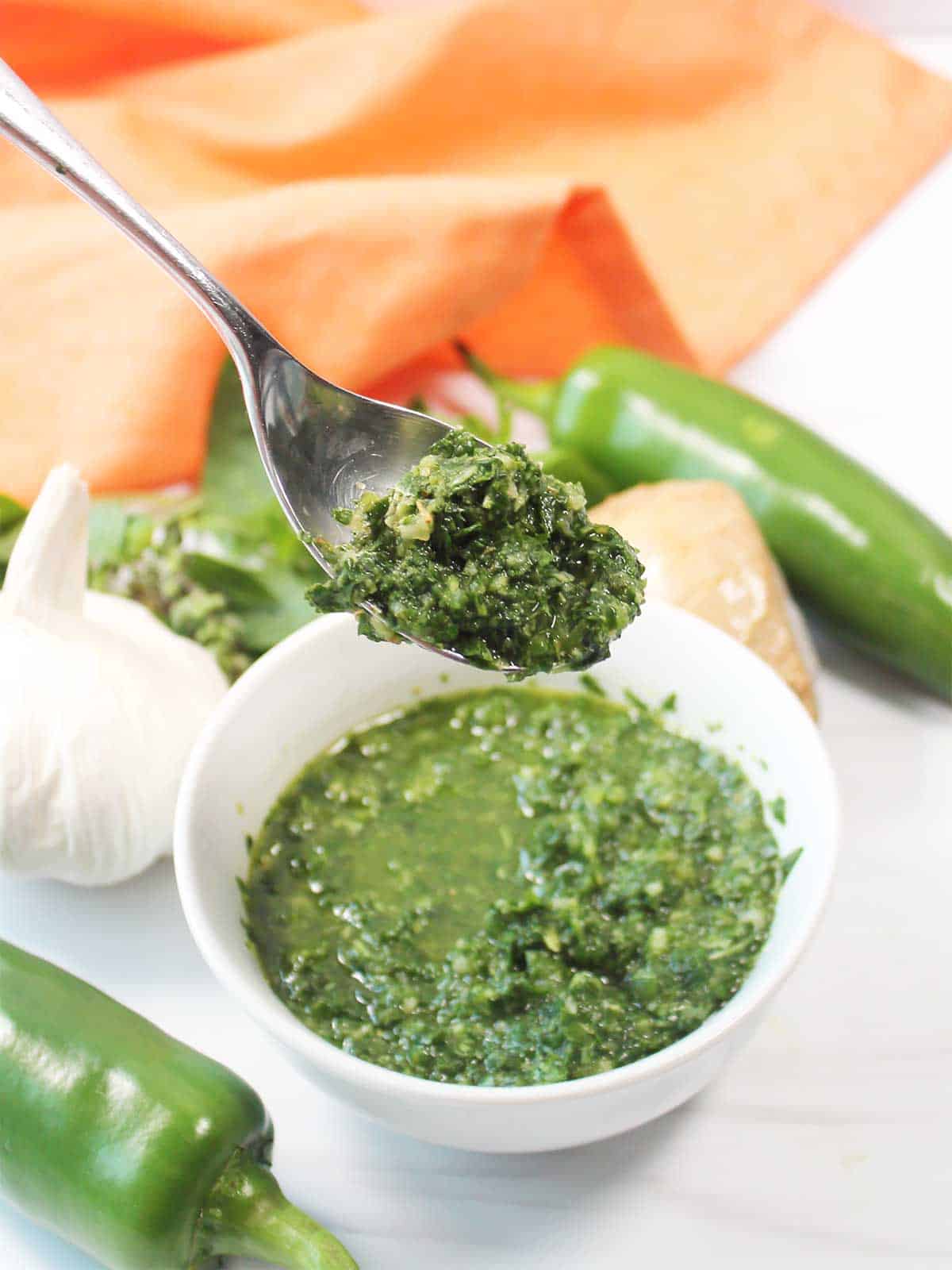 Spoonful of basil sauce over bowl.