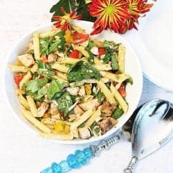 Overhead of tossed chicken salad in white bowl with turquoise server set.