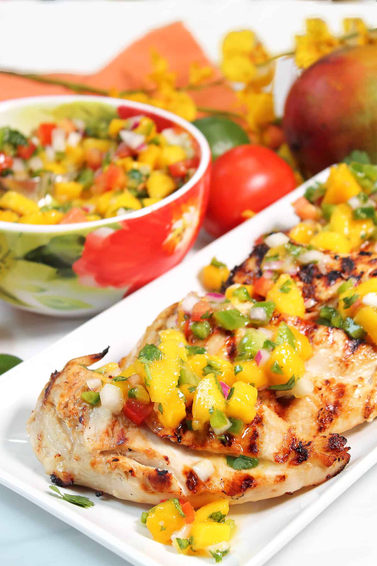 Platter of grilled chicken with salsa on top.