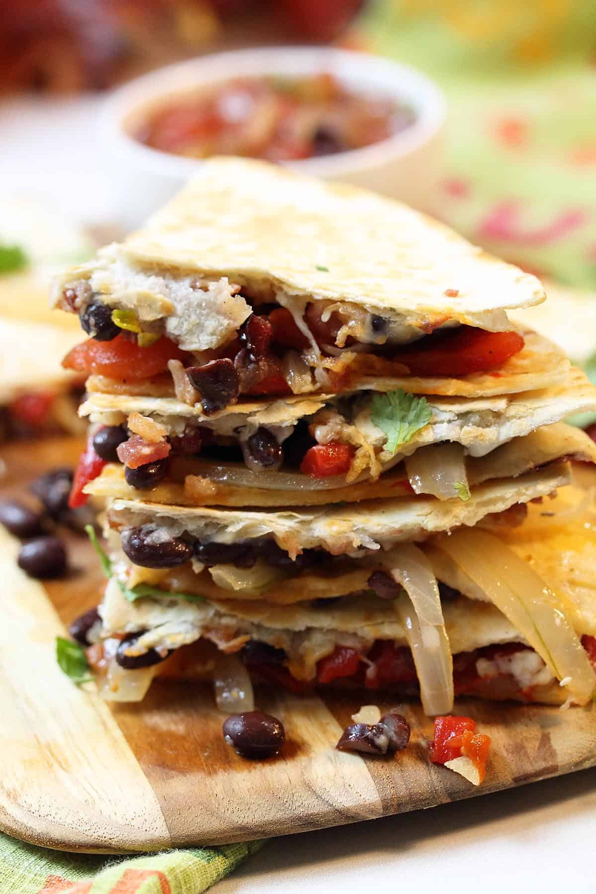 Stacked tortillas on wooden board showing filling.