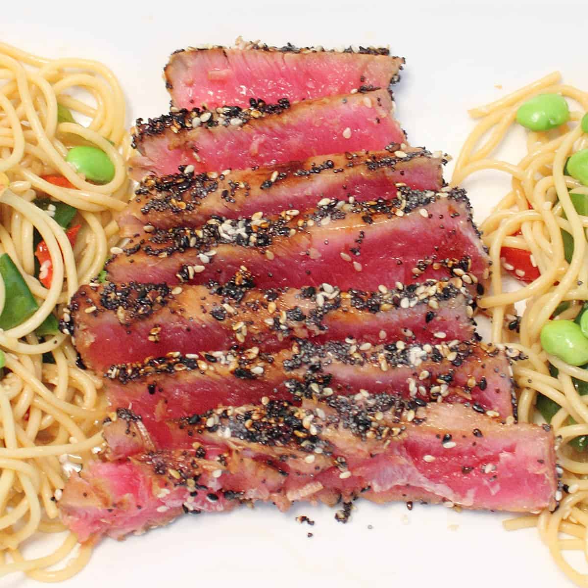 Closeup of sesame tuna dinner on white platter.