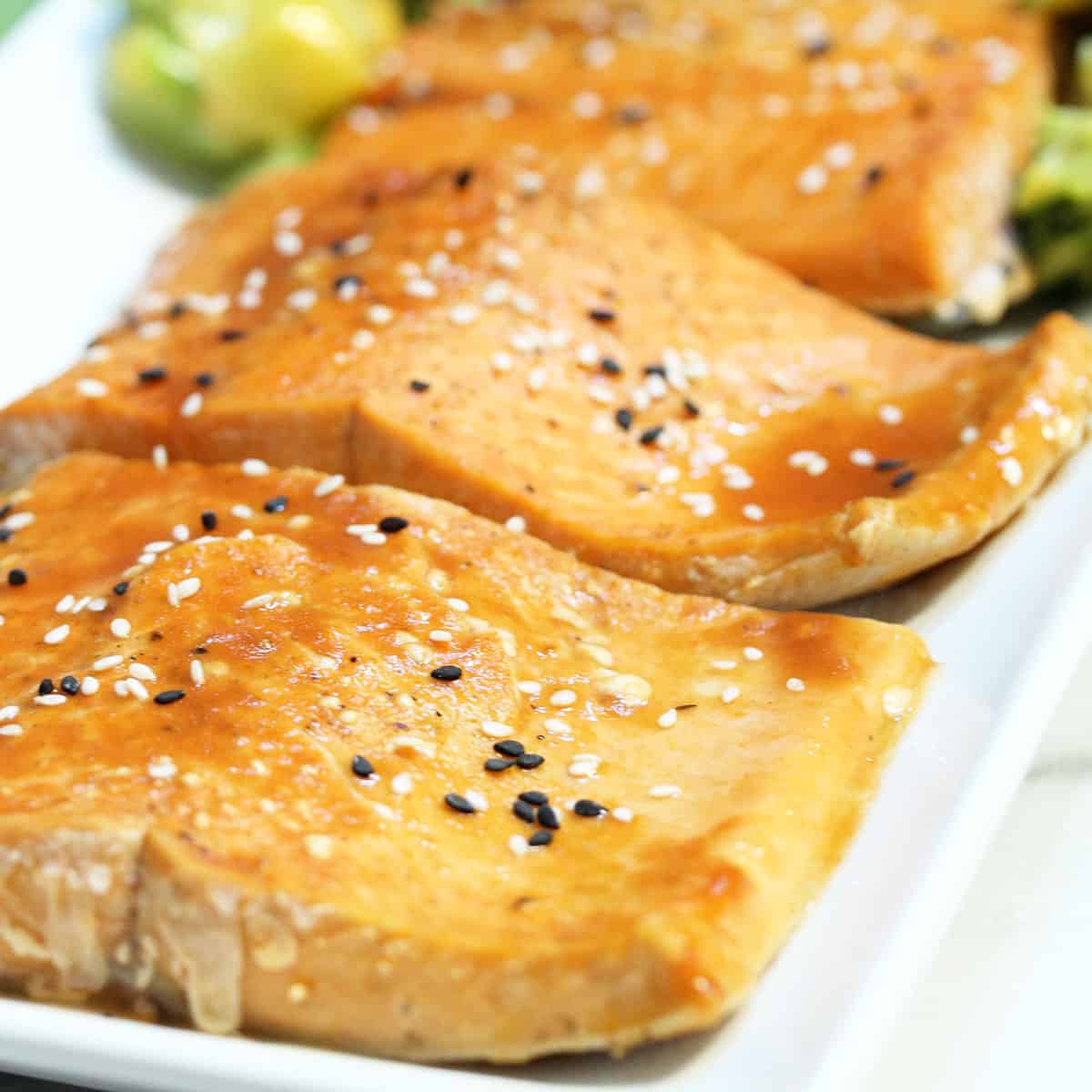 Closeup of broiled salmon on white platter.