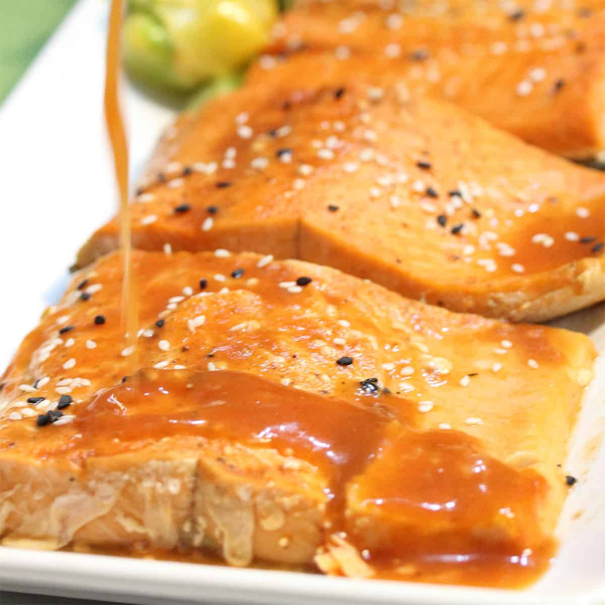 Drizzling bloody mary juice over cooked salmon on platter.
