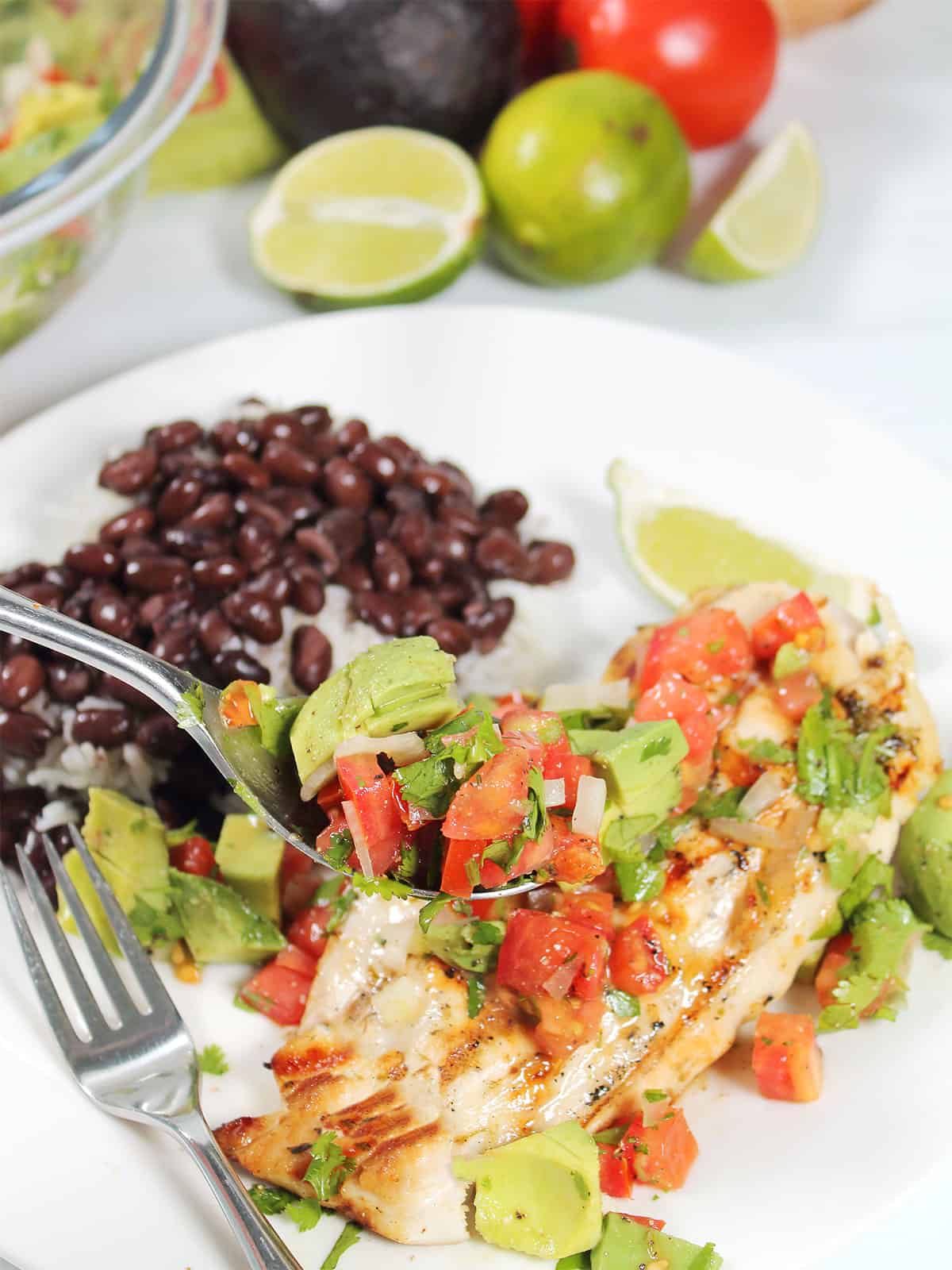 Spooning avocado salsa on top of chicken.