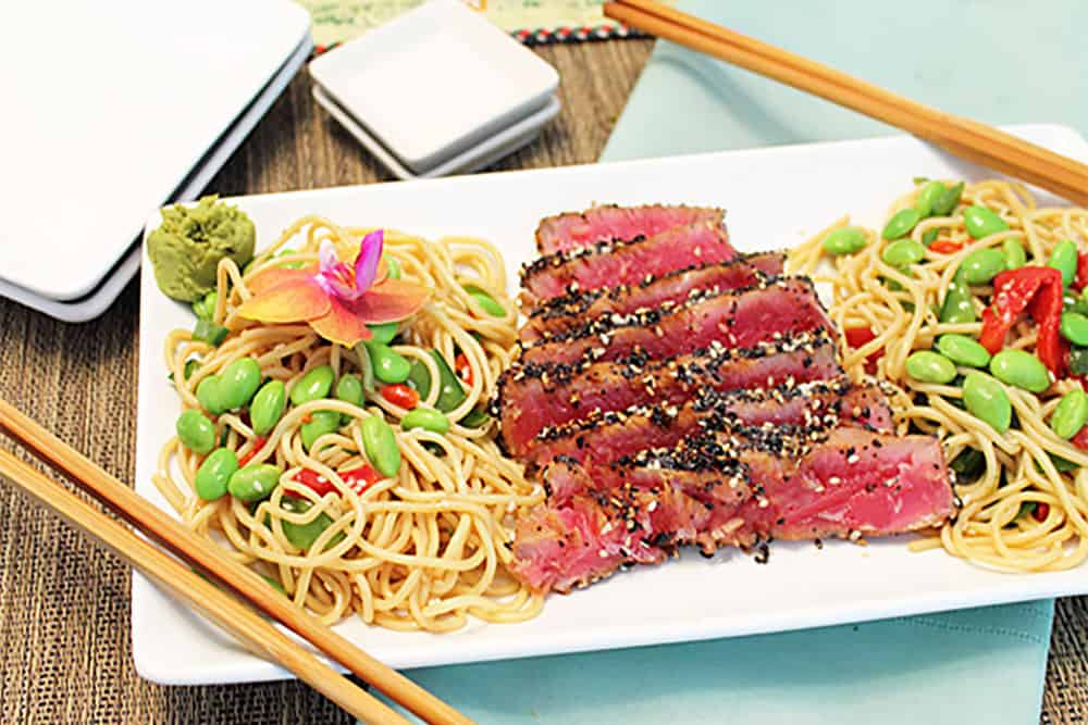 Plated seared tuna with Asian noodles and chopsticks.