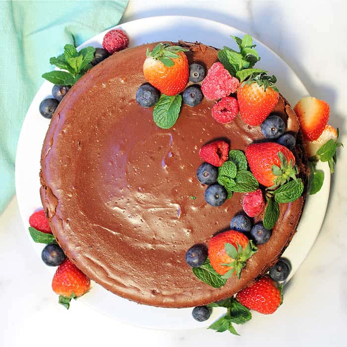 overhead of baked cheesecake garnished with fruit and mint leaves.