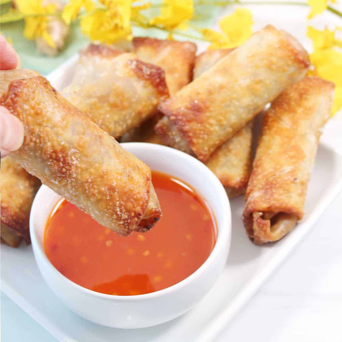 Dipping vegetable egg roll into sweet chili sauce.