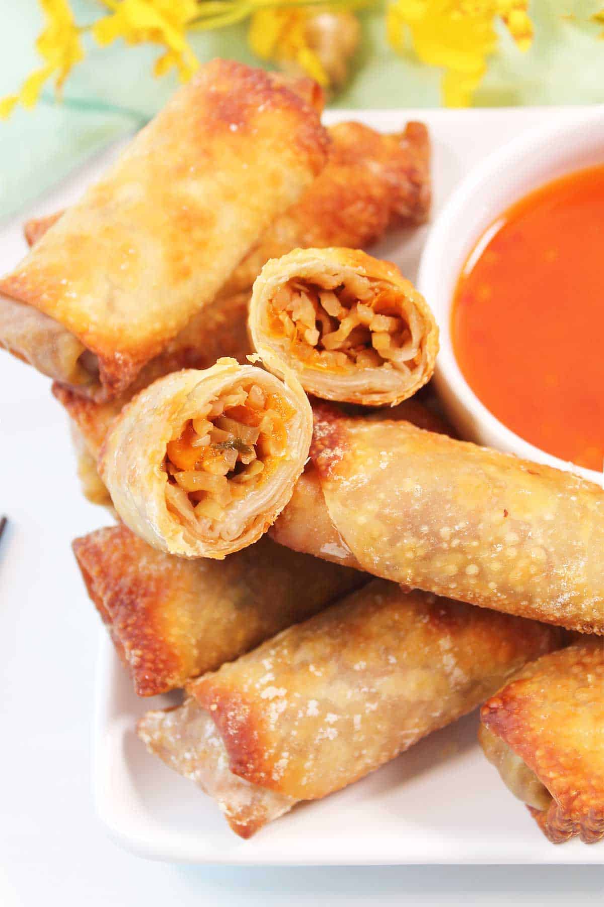 Stacked air fryer egg rolls with halved one on top.