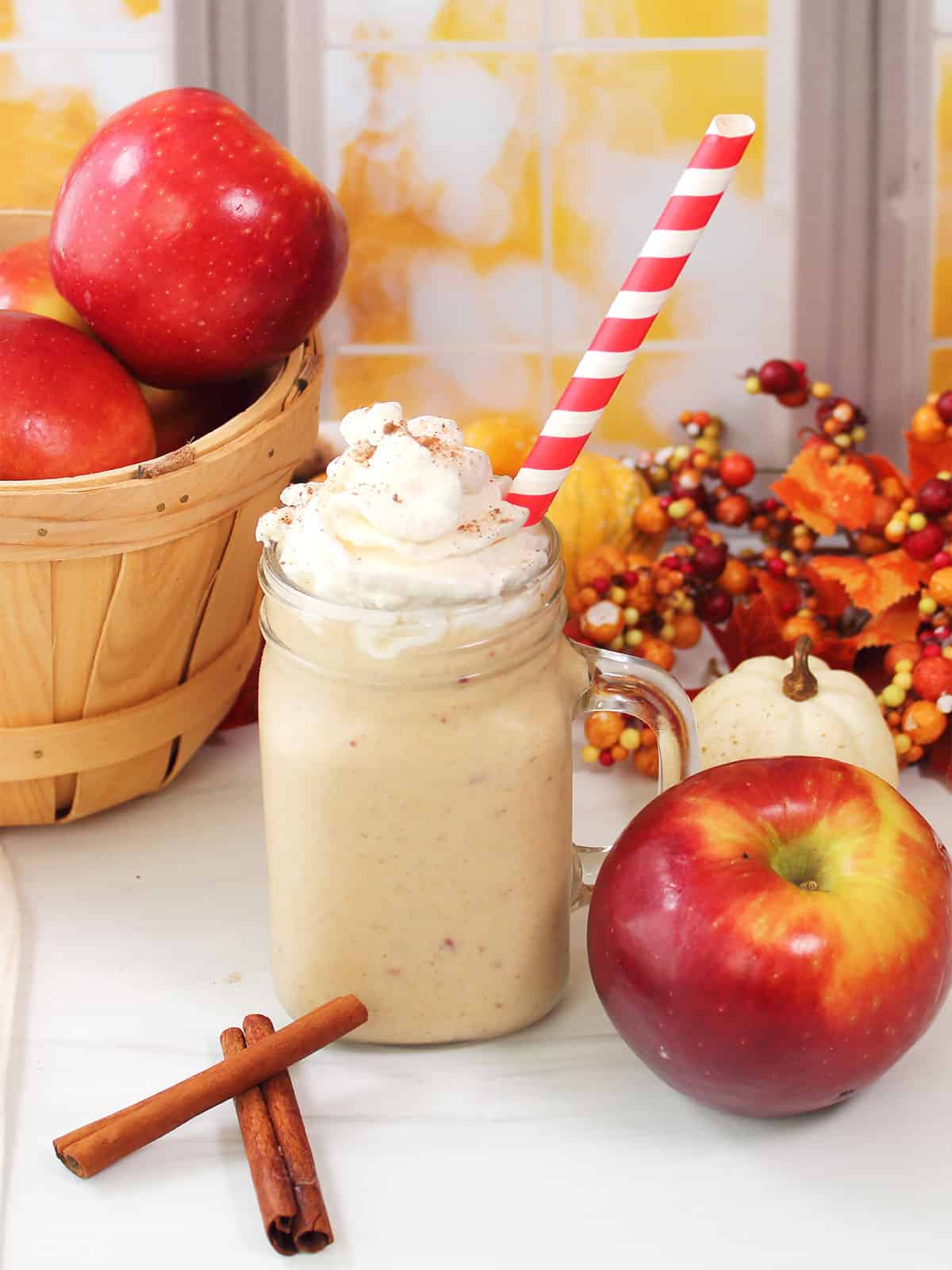 Apple Pie Smoothie in a mason jar, topped with whipped cream and a straw.