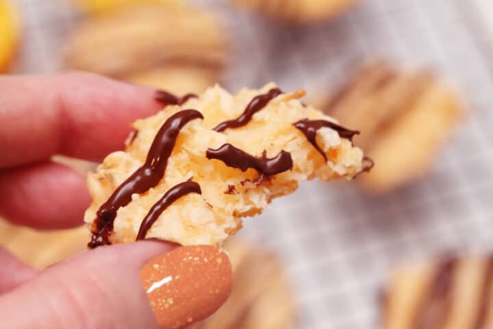 Closeup of holding a macaroon with bite out of it.
