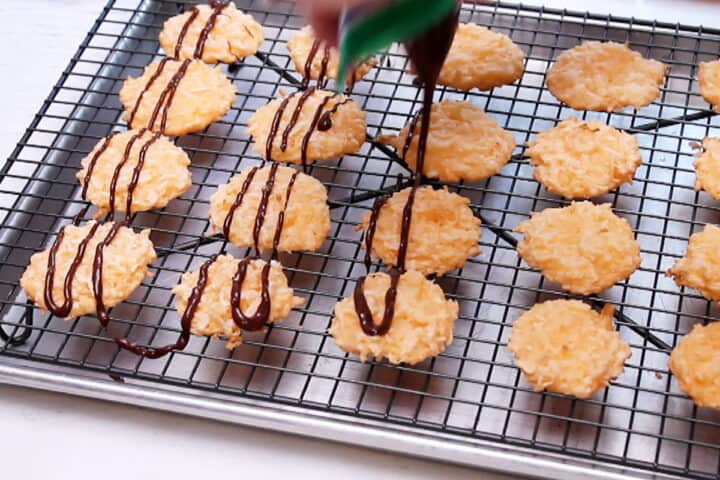 Drizzling chocolate on cooled orange macaroons.