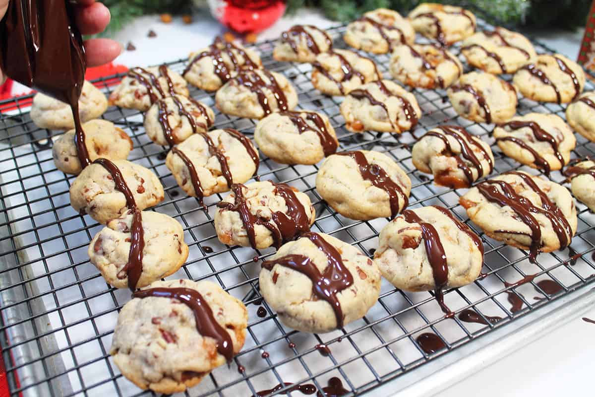 Drizzling chocolate on caramel turtle cookies.