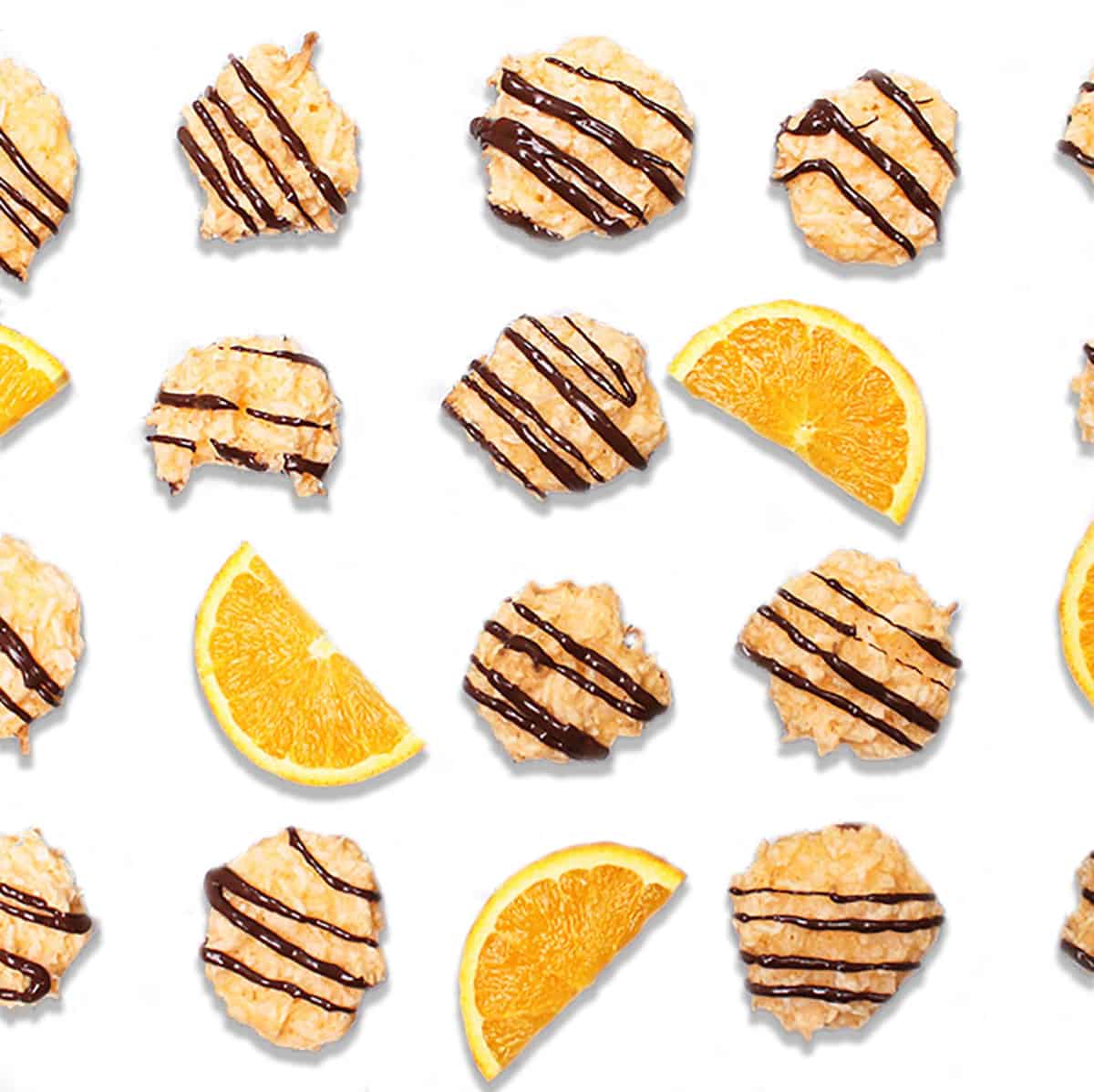 Overhead of drizzled cookies with orange slices on white table.