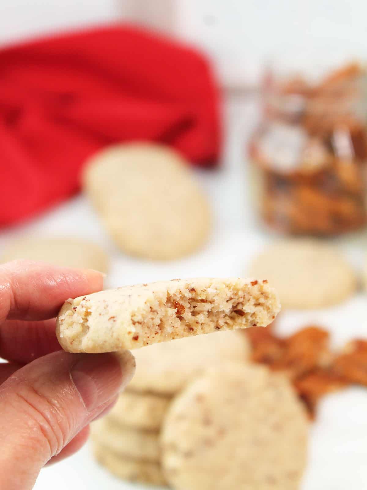 Holding pecan shortbread cookies with bite out.