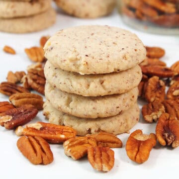 A stack of Pecan Sandies Cookies among pecans.