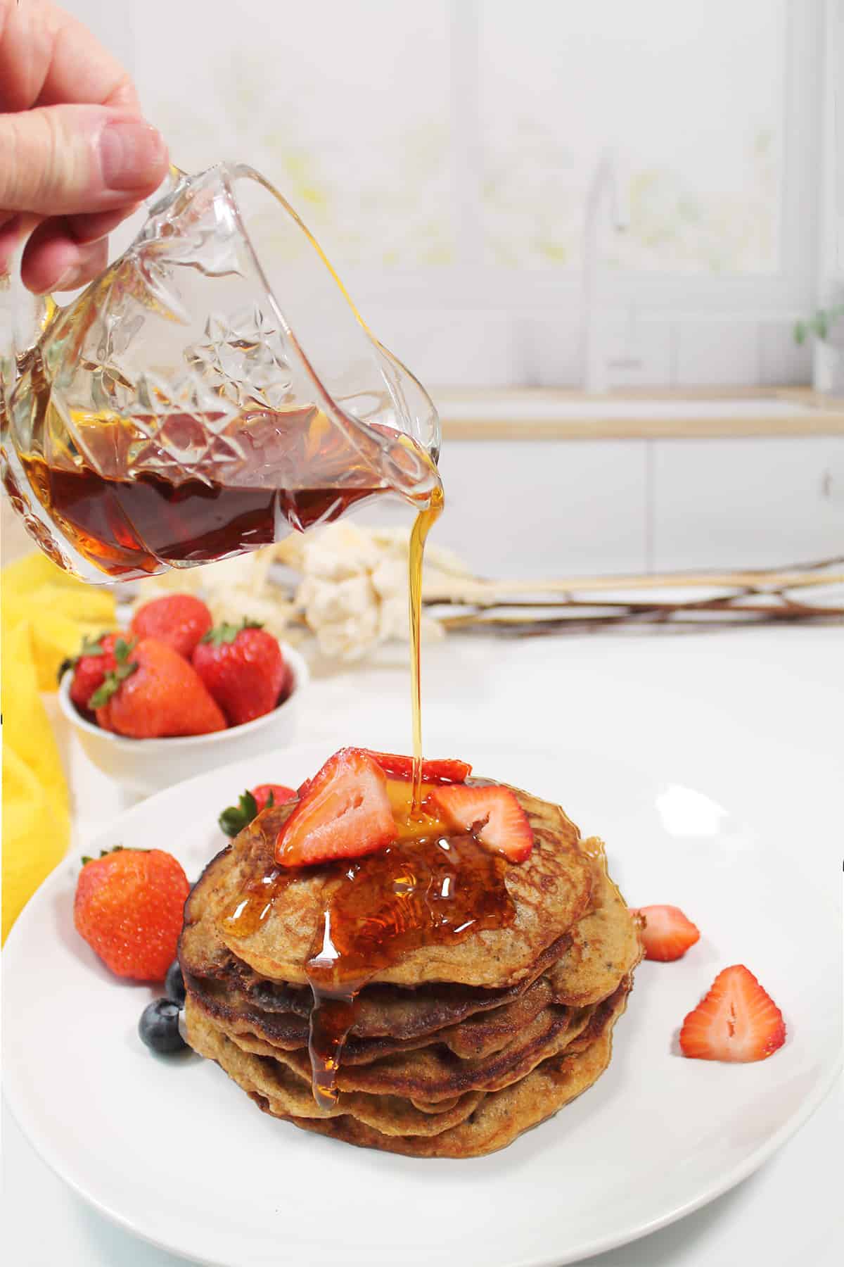 Drizzling syrup over stack of protein pancakes.