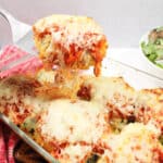 Lifting Italian stuffed chicken breast out of baking dish.