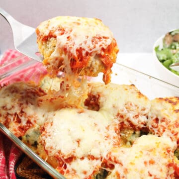 Lifting Italian stuffed chicken breast out of baking dish.