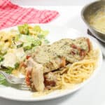 Bite of chicken on fork beside salad.
