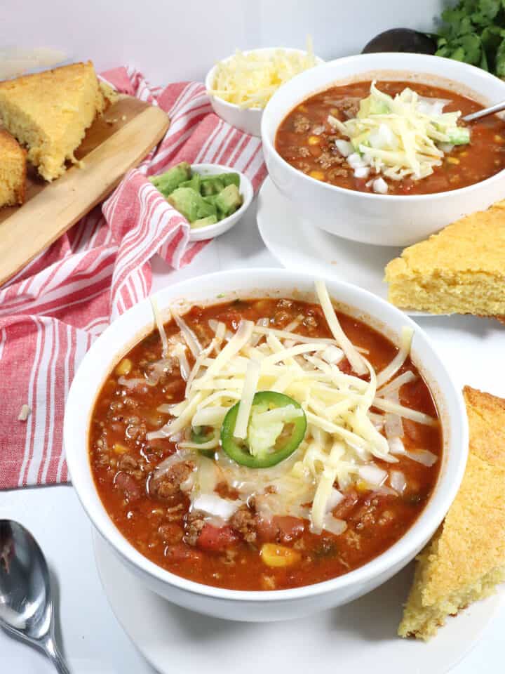 Two bowls of Spicy Crockpot Chili with garnishes on top.