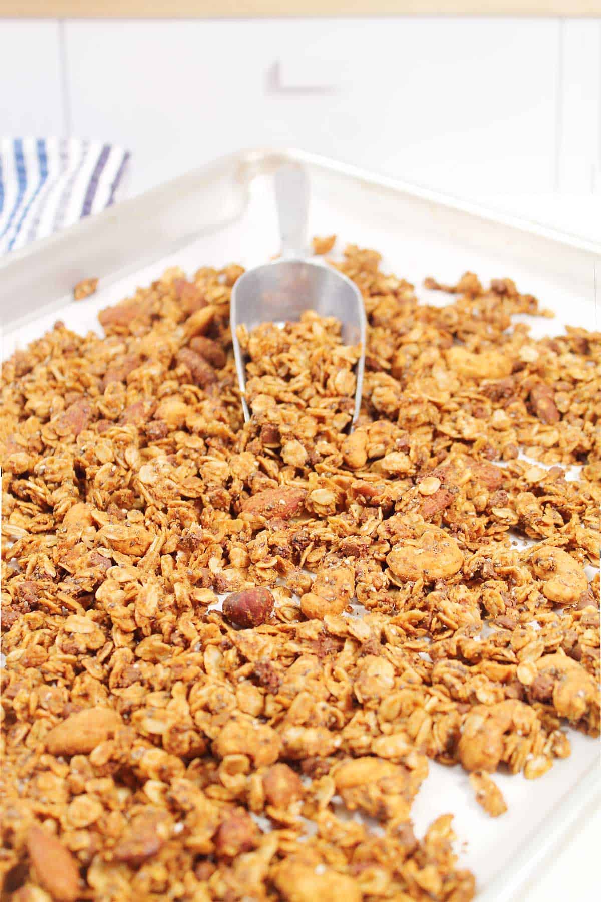 Honey almond butter granola baked on cookie sheet with scoop.