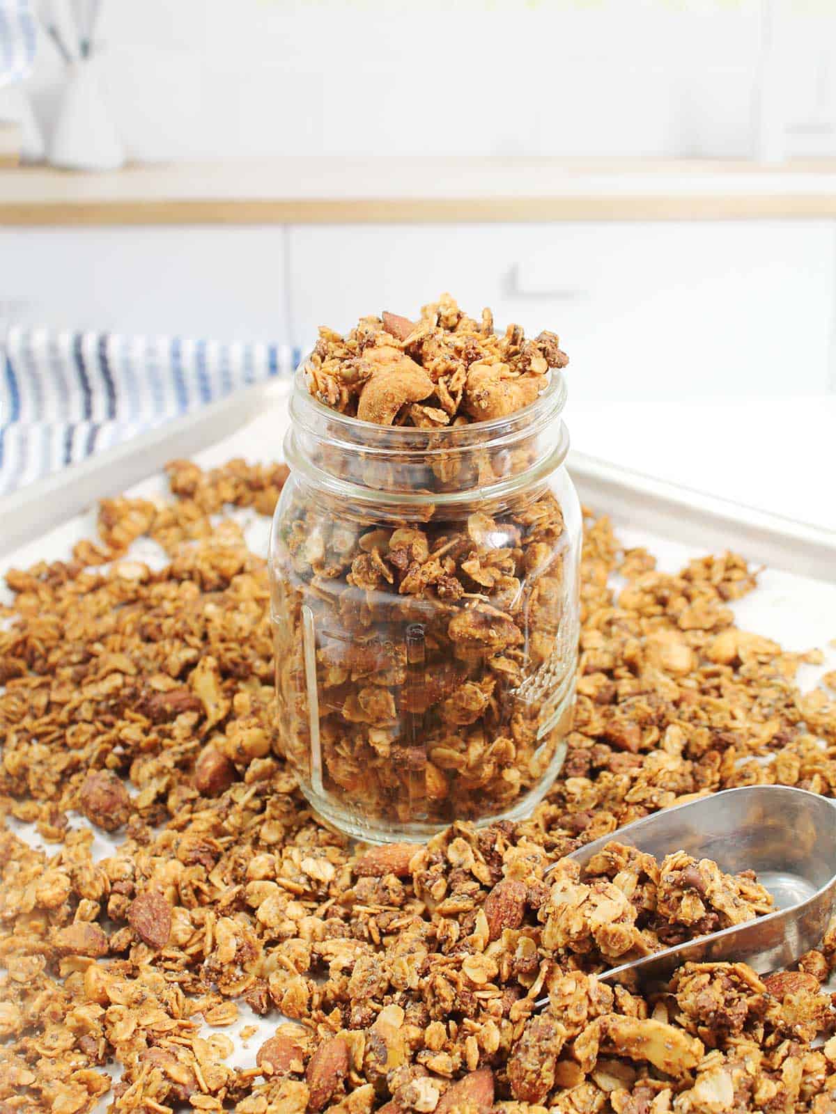 Honey Almond Butter Granola in a jar amongst loose granola.