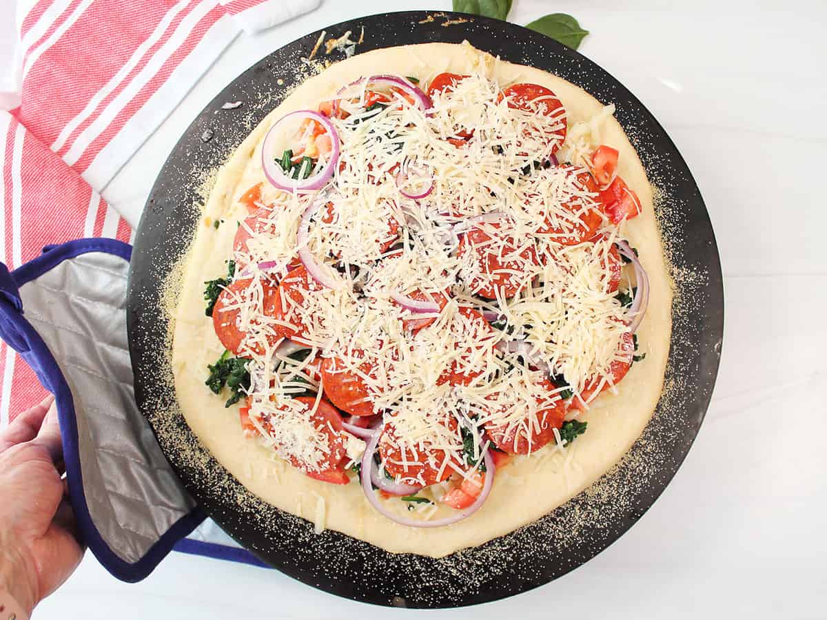 Loaded pizza on hot pizza stone for baking.
