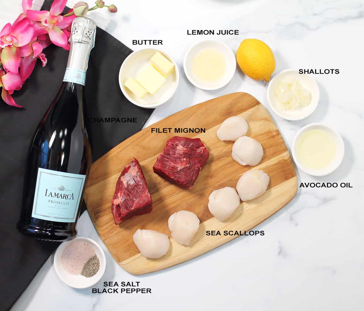 Ingredients for Steak and Scallops dinner on white marble table.