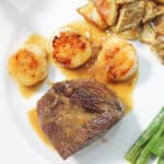 Overhead closeup of champagne butter sauce drizzled over filet mignon and scallops.