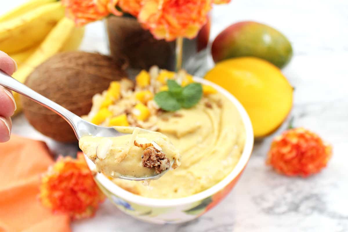 Spoonful of smoothie with full bowl & fruit in background