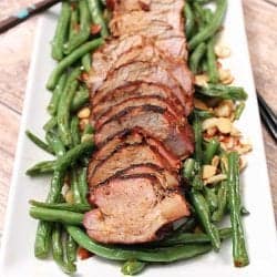 Asian Grilled Pork Loin on white platter with green beans.