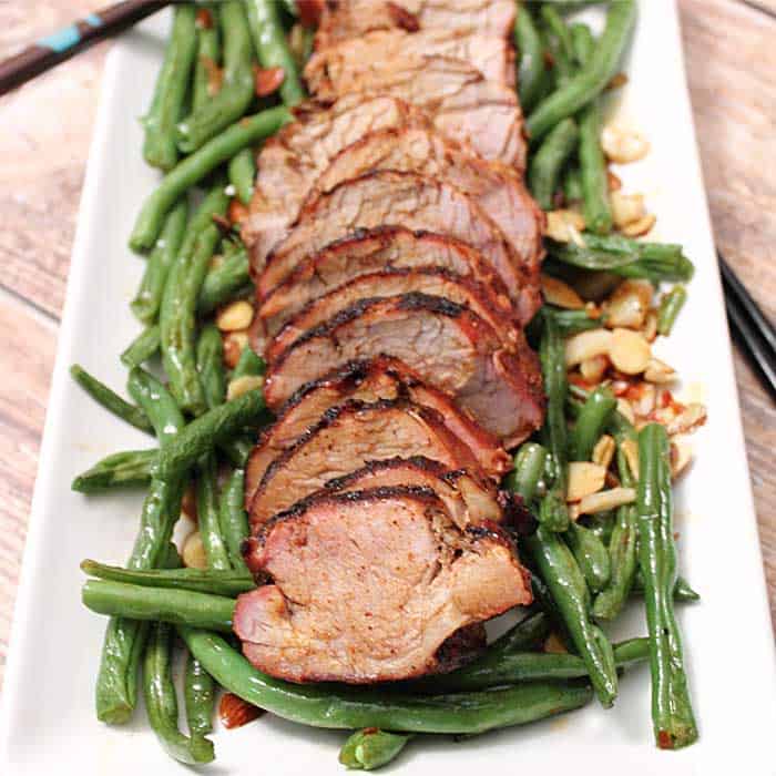 Asian Grilled Pork Loin on white platter with green beans.