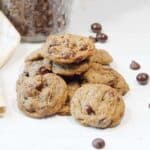 Cookies in a pile with scattered chocolate chips and espresso beans.