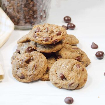 Cookies in a pile with scattered chocolate chips and espresso beans.