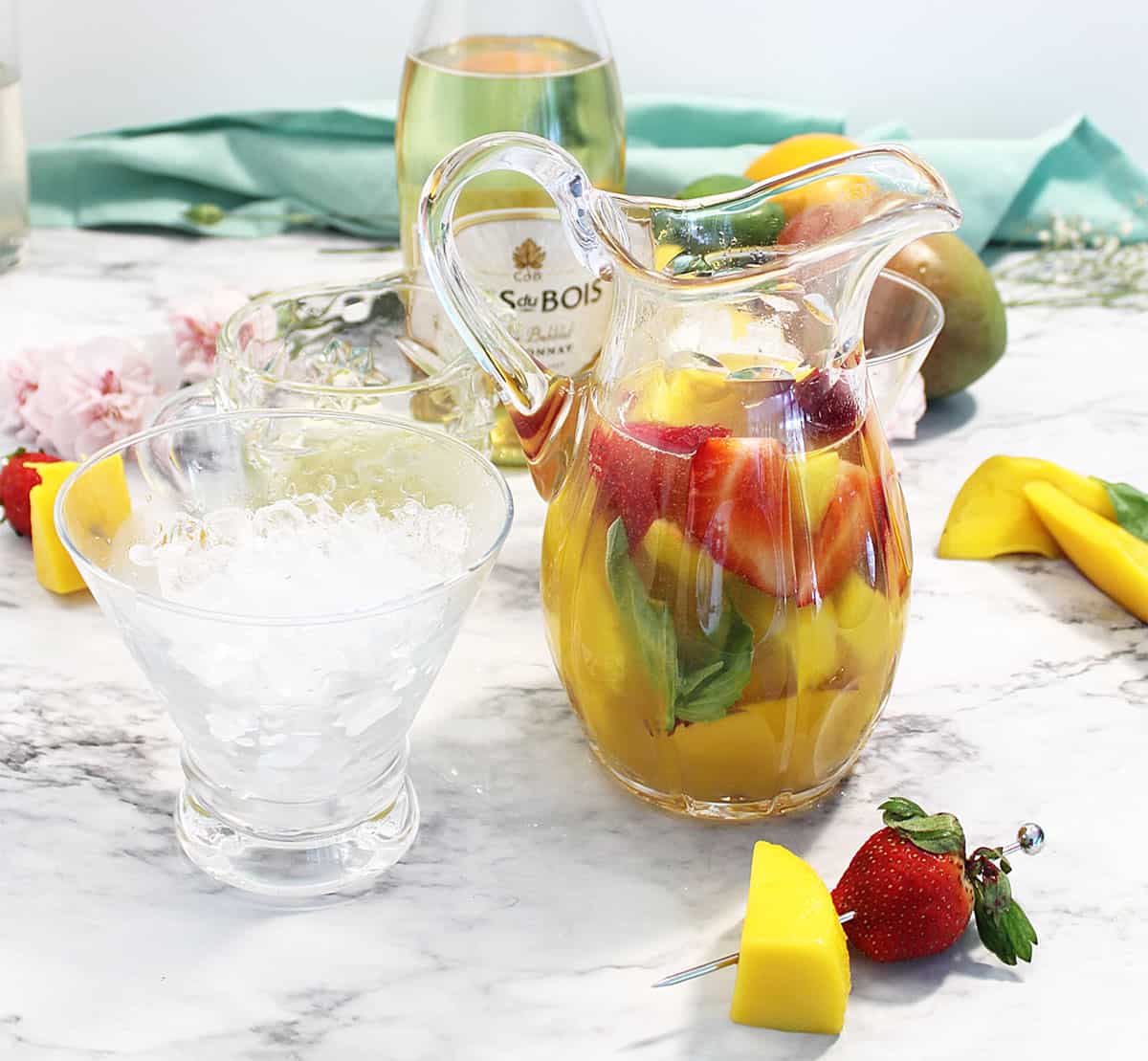 Mango Basil Cocktail in pitcher on white table.