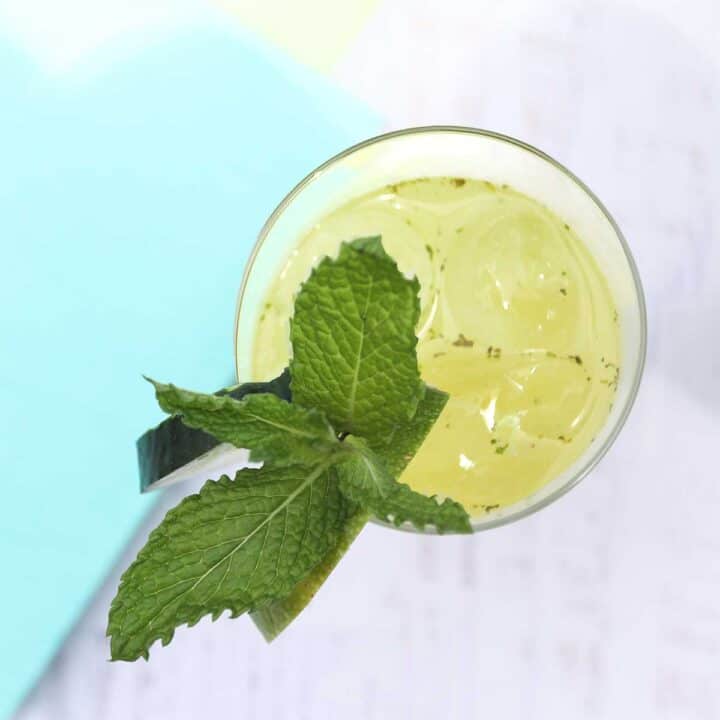 Overhead looking into inside of glass with cucumber and mint garnish.
