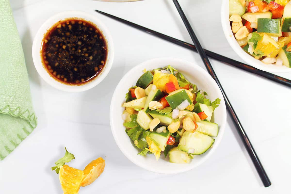 Overhead of Thai salad in bowl with side of dressing.