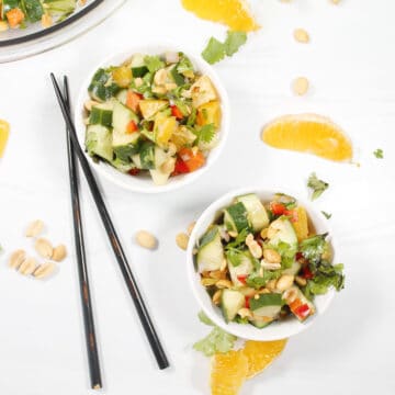 Overhead of two bowl of garnished salad with chopsticks.