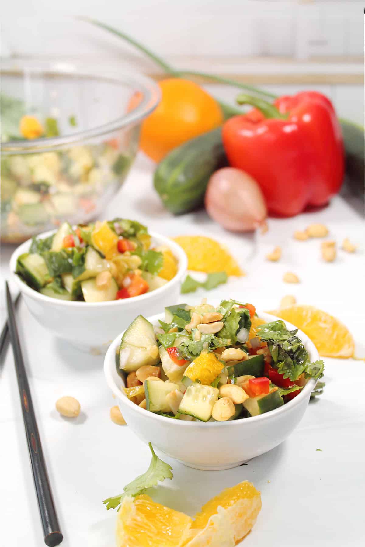 Two bowls of Thai Cucumber Salad with peanuts with scattered oranges.