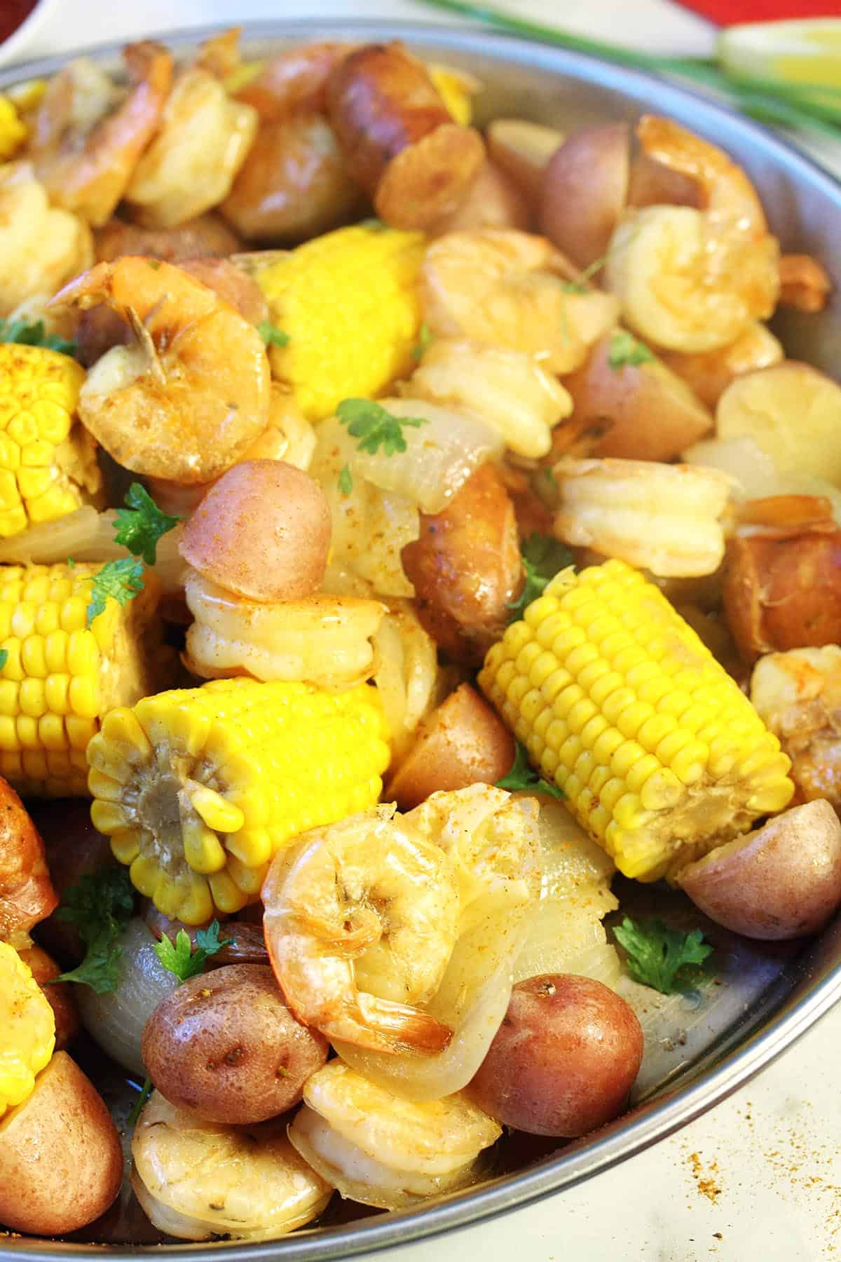 Closeup of boil in round pan showing corn shrimp and potatoes.