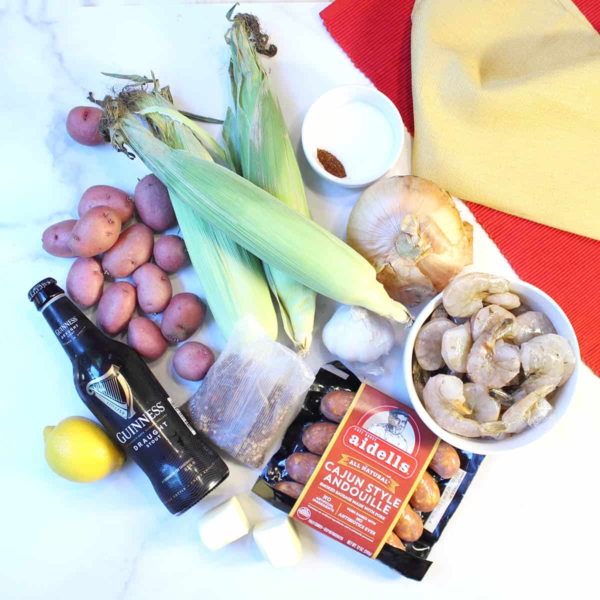 Ingredients for shrimp boil laid out on white table.