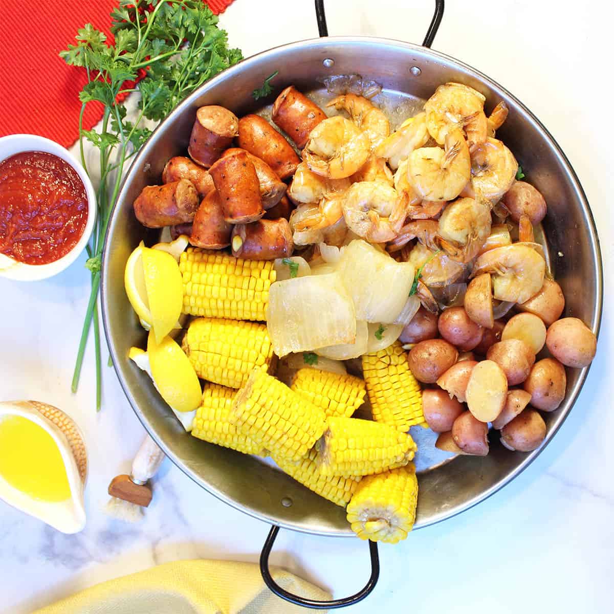 Overhead showing each seafood boil ingredient in round pan.