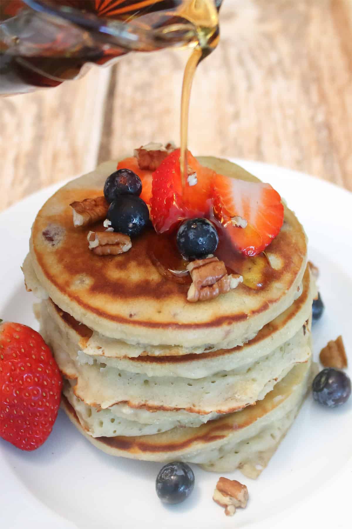 Pouring syrup over pancakes with bananas.