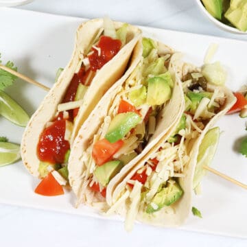 Showing chicken tacos stuffed with fillings.