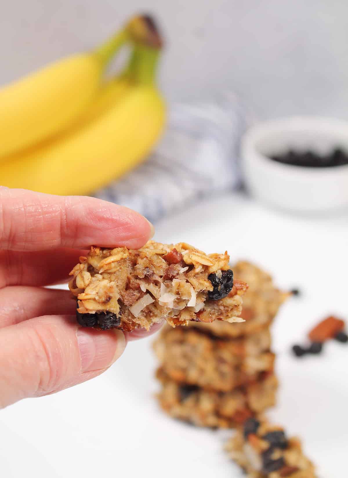 Holding oatmeal banana breakfast cookie with bite out of it.