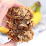 Holding stack of cookies in front of bananas.