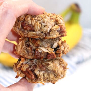 Holding stack of cookies in front of bananas.