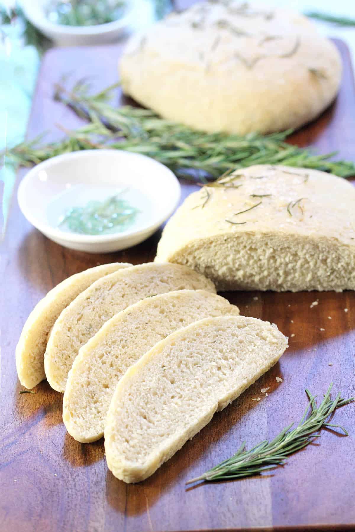 Long wooden serving board with 2 breads on it and dipping saucers.
